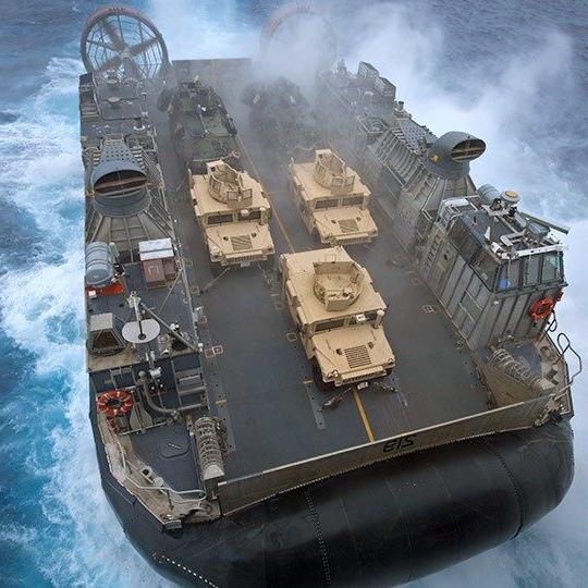 航拍的巨大军用气垫船在海上装有移动天线，载着三辆悍马车 