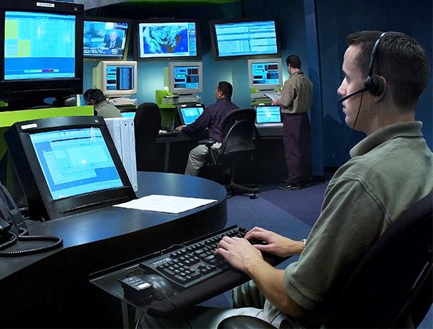 三名Viasat网络运营员工在电脑和电视监视器上监控数据